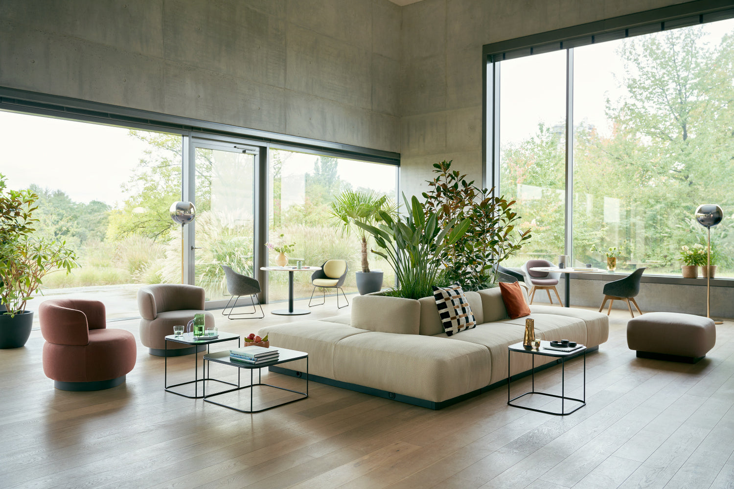 se:living | plant bench – Sofa – Moderne Lounge mit hellem Sofa, gepolsterten Sesseln, Glastischen und Pflanzen, große Fenster zur Natur.