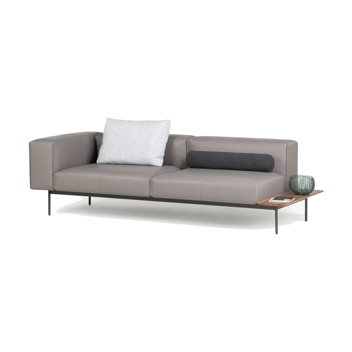 Convert Sofa als 3-Sitzer von Prostoria in taupefarbenem Leder, freigestellt vor weissem Hintergrund, Schrägansicht mit linker Armlehne, dunkler Nackenrolle und seitlicher Holzablage.