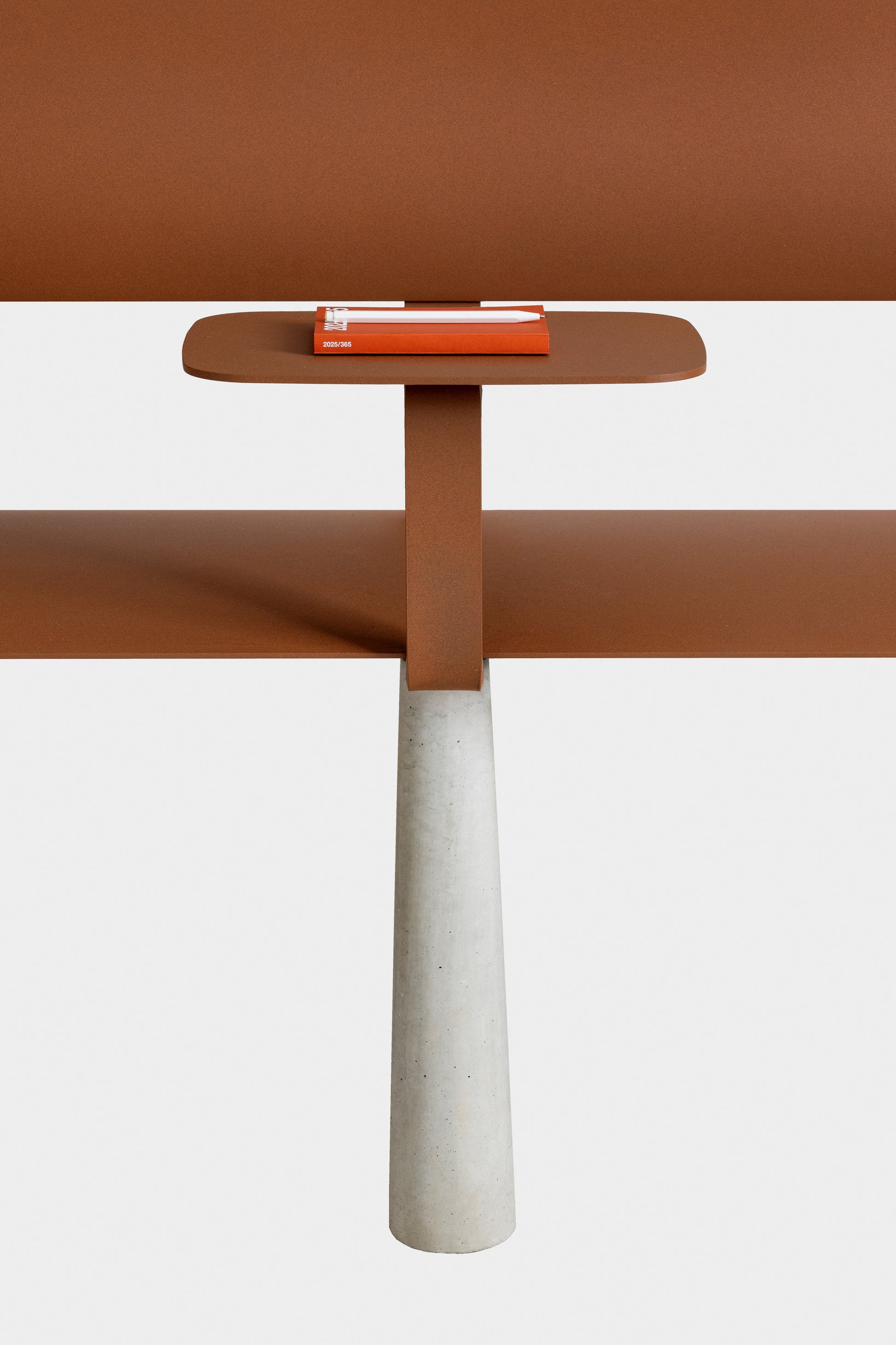 Ben – Bank – Tisch mit braunem Tischblatt und grauem Betonsockel; darauf liegt ein rotes Notizbuch.