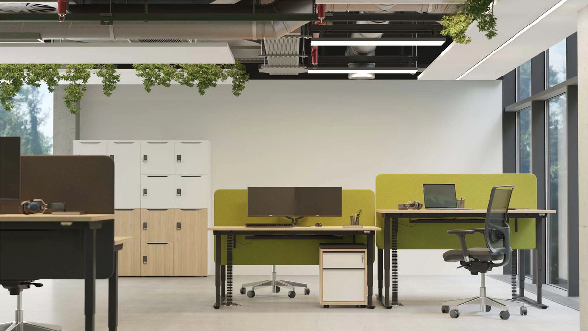 Easy | Bench – Bench-Arbeitsplatzsystem – Büroansicht mit zwei Stehpulten, grünen Trennwänden, Monitore, und einem Rollcontainer in Holzoptik. Fenster mit Ausblick.