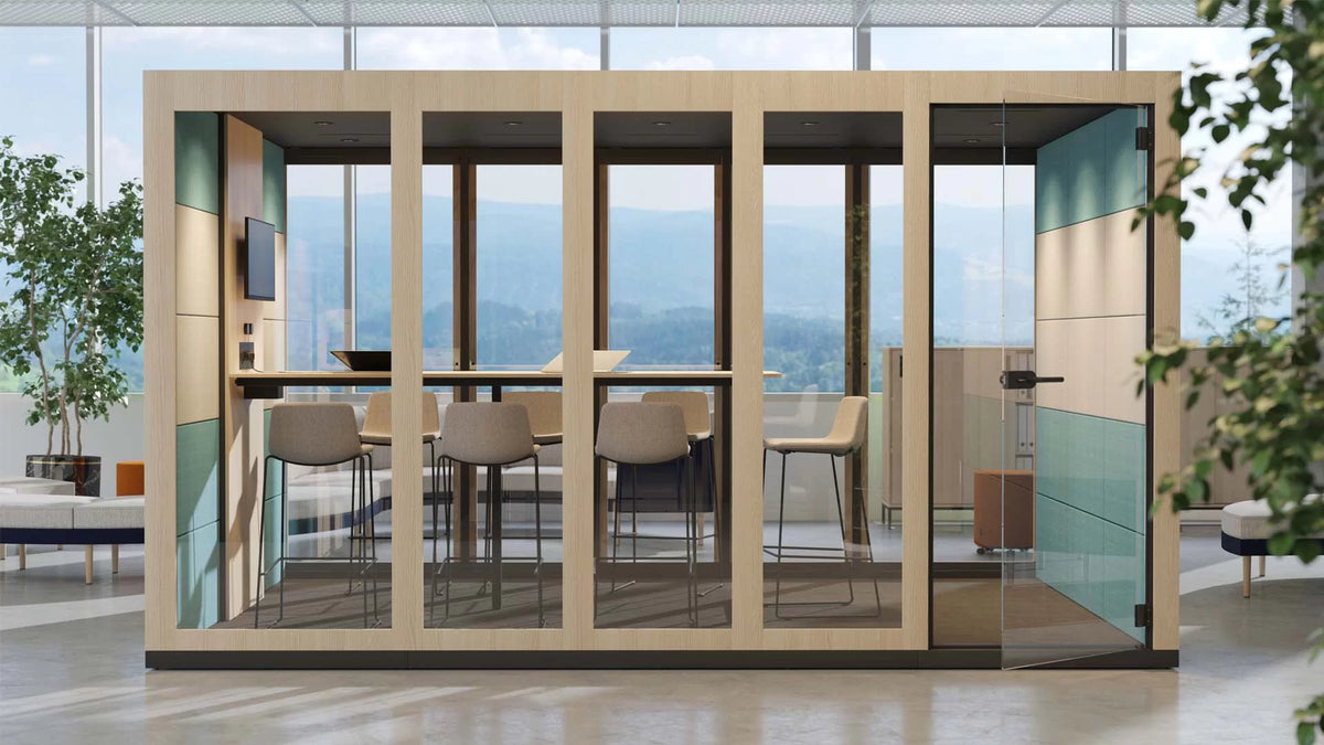 Silent Room XL | Meetingbox – Meetingbox – Modulare Bürokabine mit Glaswänden, Holzelementen und Stehtisch, umgeben von Pflanzen und modernem Interieur.