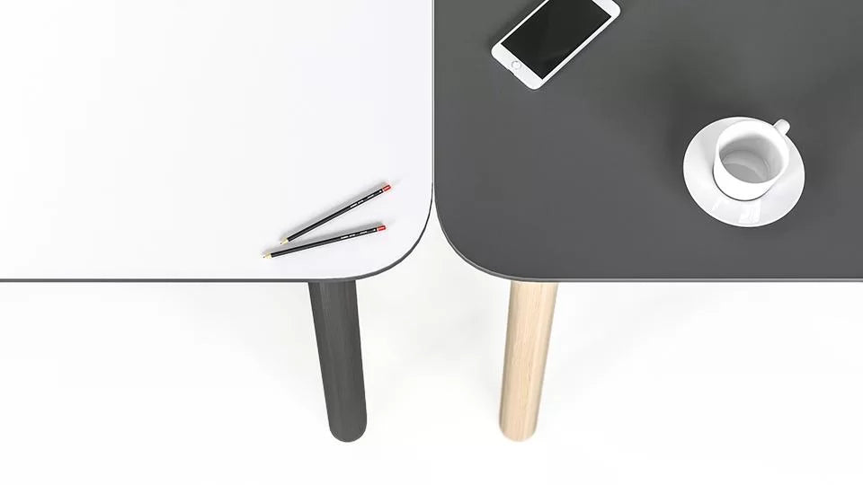 Nova Wood | Bench – Bench-Arbeitsplatzsystem – Zwei Tische, einer in Weiss mit schwarzen Stiften, der andere in Grau mit Smartphone und Kaffeetasse, helle Holzbeine.