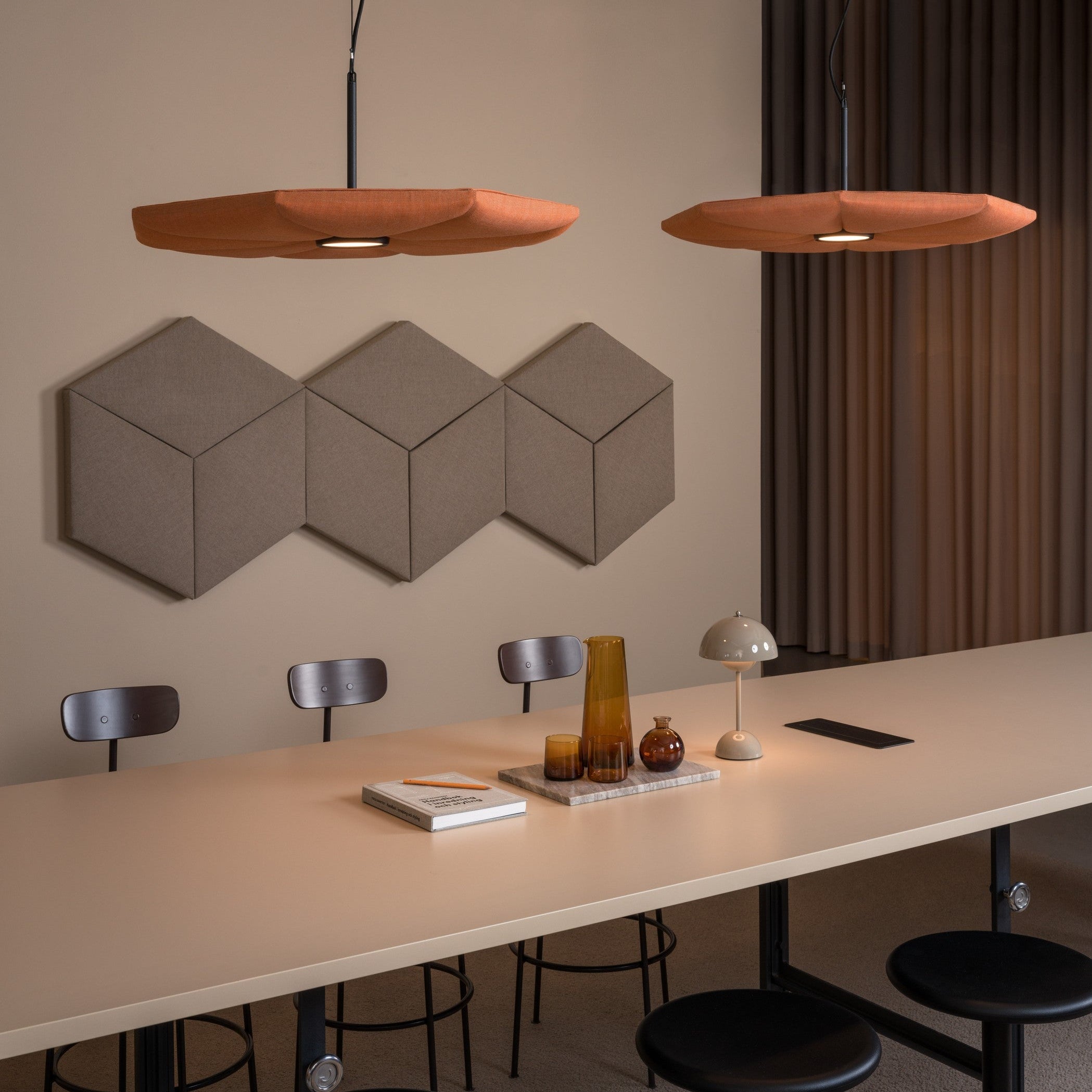 Hikari Ceiling – Akustische Deckenleuchte – Schlichtes, langes Tisch-Setup mit schwarzen Stühlen, dekoriert mit Lampen, Vasen und einem Buch auf einem Tablett.