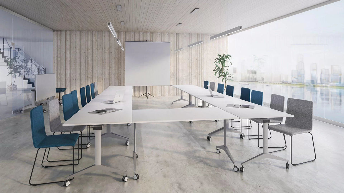 Klapptisch | Flip-Top – Klapptisch – Moderne Konferenzraum mit einem grossen weissen Tisch, blauen und grauen Stühlen, Flipchart und Fensterfront.