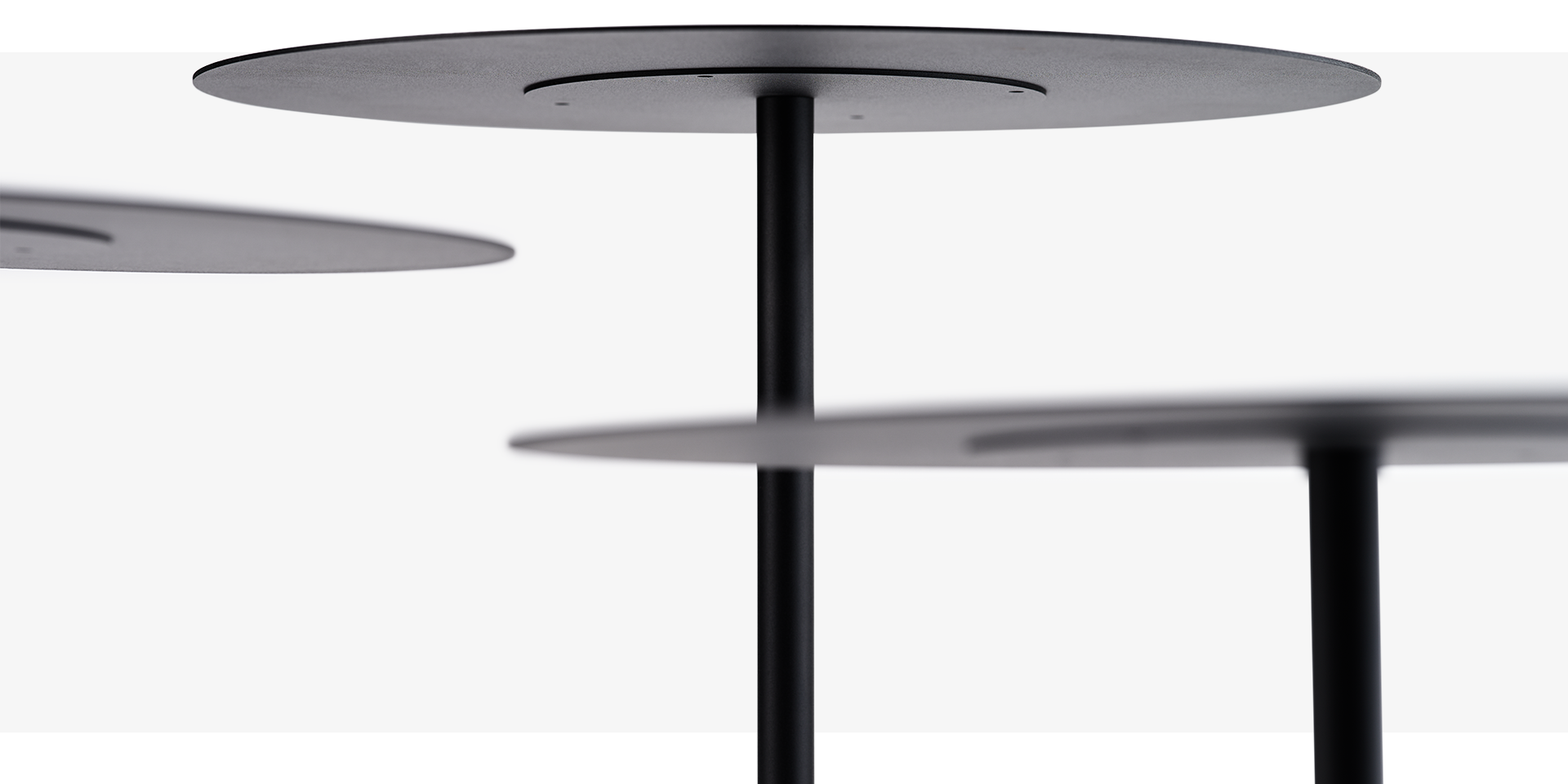 se:tea – Beistelltisch – Drei schwarze Tischplatten mit einem zentralen, runden Fuß aus Metall, vor einem neutralen Hintergrund.