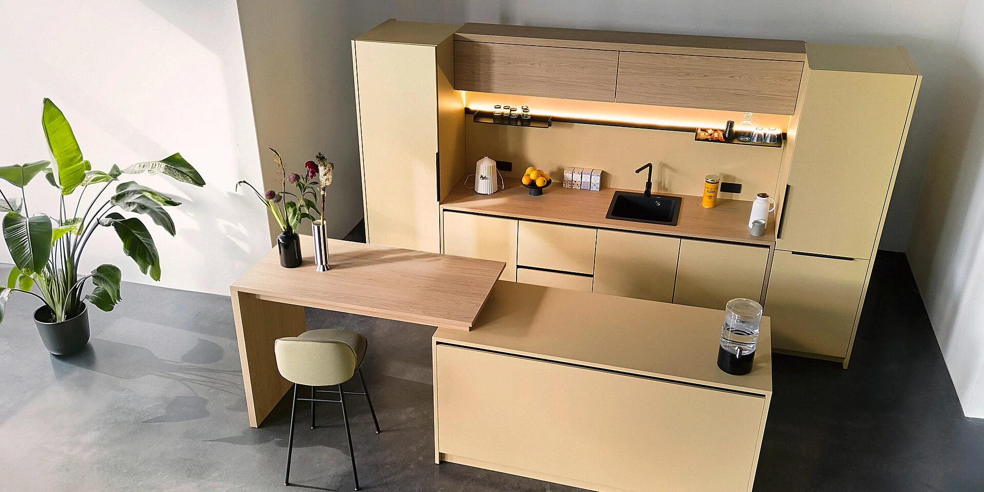 se:café bar – Bar – Moderne Küche mit hellen Holzoberflächen, schwarzem Spülbecken und Barbereich. Pflanze und Dekoration auf der Theke.