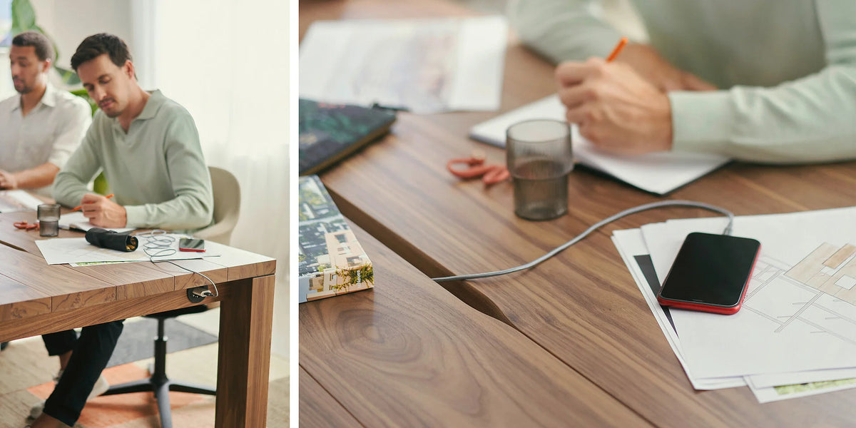 se:café table – Team-Tisch – Holztisch mit mehreren Arbeitsunterlagen, Smartphone und Stift; zwei Personen sitzen am Tisch und arbeiten.