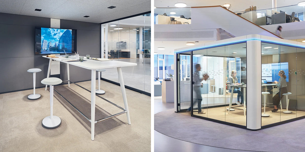 Meetingbox se:cube max: Besprechungsraum mit Stehtisch, weissen Hockern und Fernseher an der Wand. Glaswände trennen den Raum von der Umgebung.