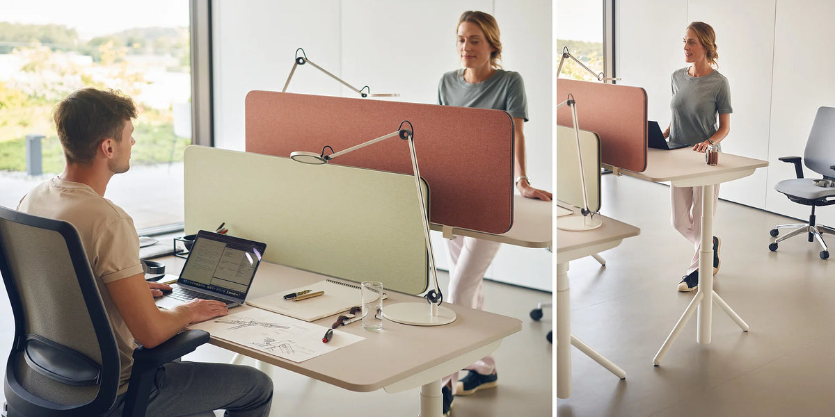 Elektrisch höhenverstellbarer Schreibtisch se:lab e-desk A: Zwei Schreibtische mit akustischen Trennpaneelen in einem modernen Büro; Person arbeitet an einem Stehpult.