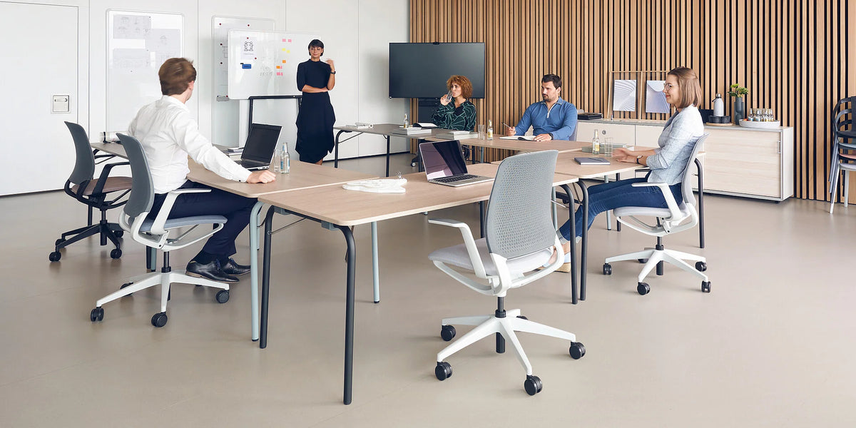 se:lab fold – Klapptisch – Konferenzraum mit einem langen Tisch und sechs Stühlen. Personen sitzen und diskutieren, Präsentationswand im Hintergrund.