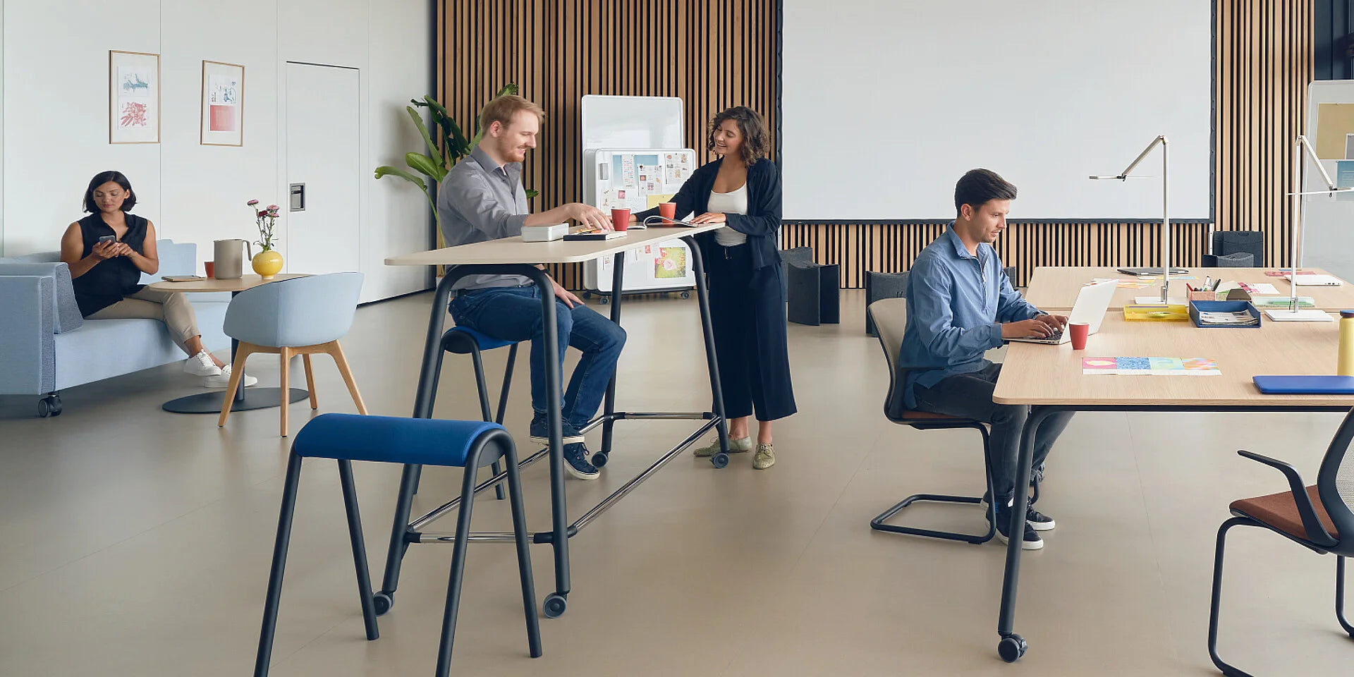 se:lab high desk – Hochtisch – Offene Büroumgebung mit mehreren Personen. Hochstühle und ein Stehtisch, Couch und Arbeitsplätze mit Laptops.