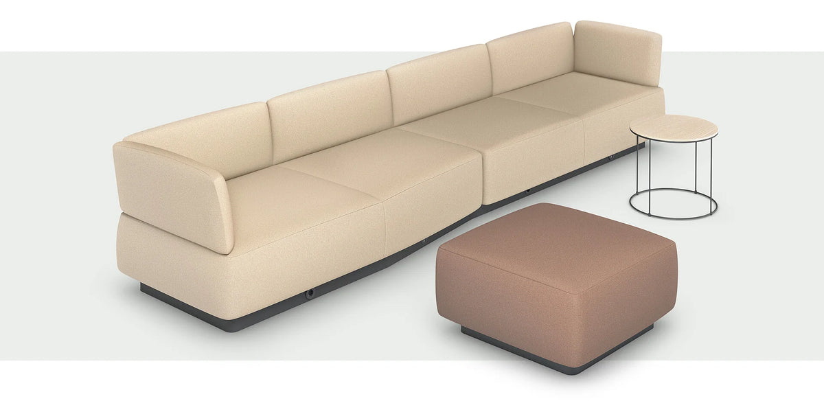 se:living – Sofa – Beige modulare Sitzlandschaft mit abgerundeten Kanten, dazu ein runder Beistelltisch mit schwarzem Gestell und braotem Hocker.