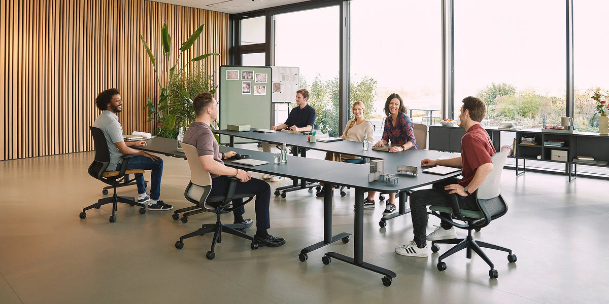 Ergonomischer Bürostuhl se:motion net: Modernen Besprechungsraum mit sechs Personen an einem grossen Tisch. Pflanzen und grosse Fenster im Hintergrund.