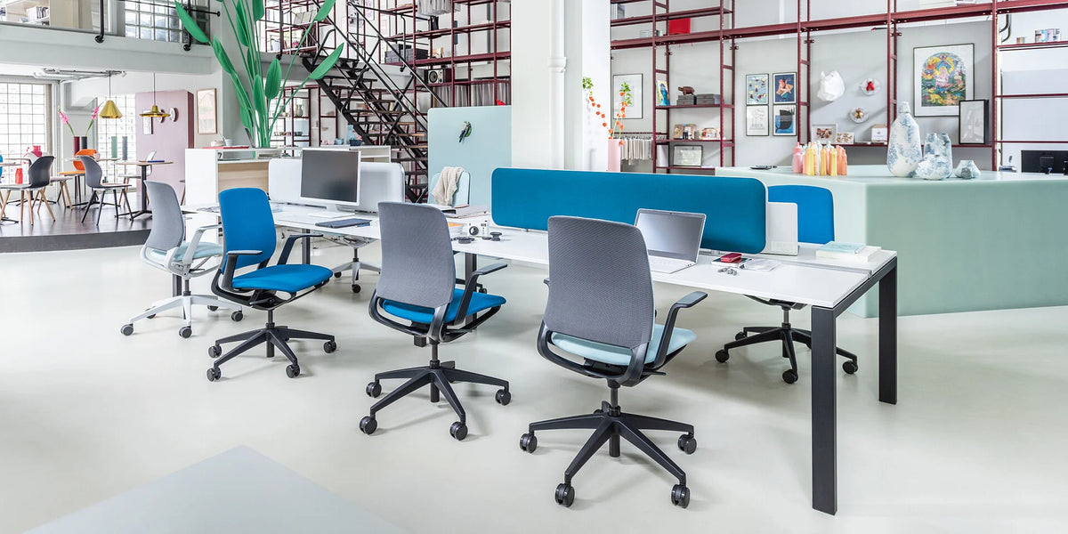 se:motion – ergonomischer Bürostuhl – Moderne Büromöbel mit mehreren Arbeitsplätzen, hellen Stühlen in Blau und Grau, und einem langen Tisch mit Bildschirm.