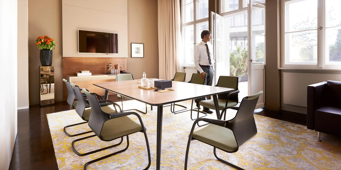 mastermind – Konferenztisch – Konferenzraum mit einem Holztisch, sechs Stühlen in Grün und einem großen Fenster mit Aussicht auf die Terrasse.