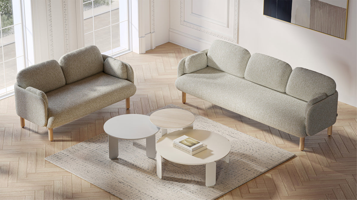 MYAMI | Sofa – Sofa – Zwei hellgraue Sofas mit Holzbeinen auf einem hellen Holzboden, umgeben von runden Tischen und einem Teppich.