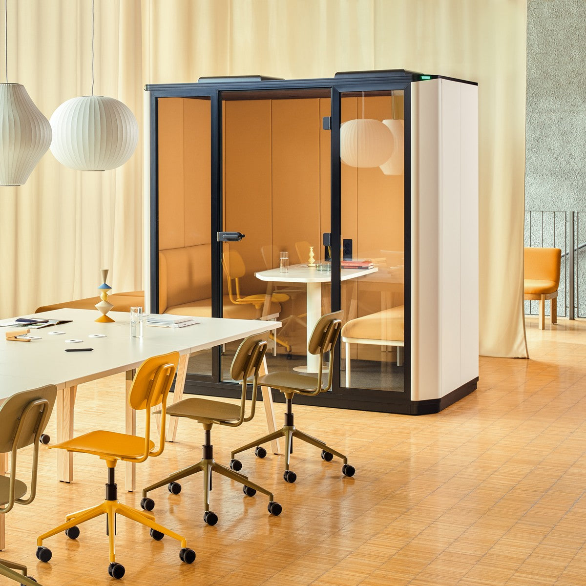 Coda 4-Personen-Akustikkabine von MDD hinter einem Arbeitstisch mit Stühlen