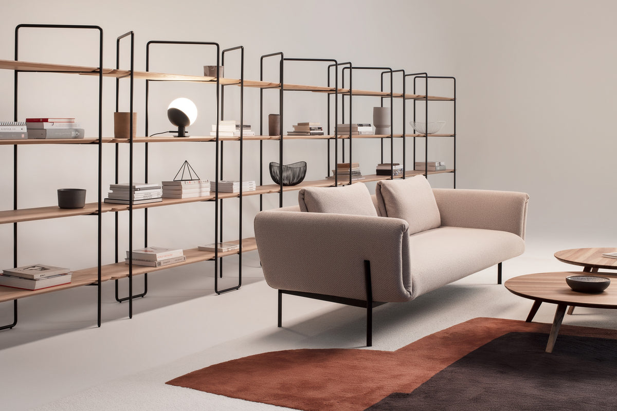 Impression Sofa von Prostoria in Beige vor einem Regalsystem, Milieuaufnahme. © Prostoria
