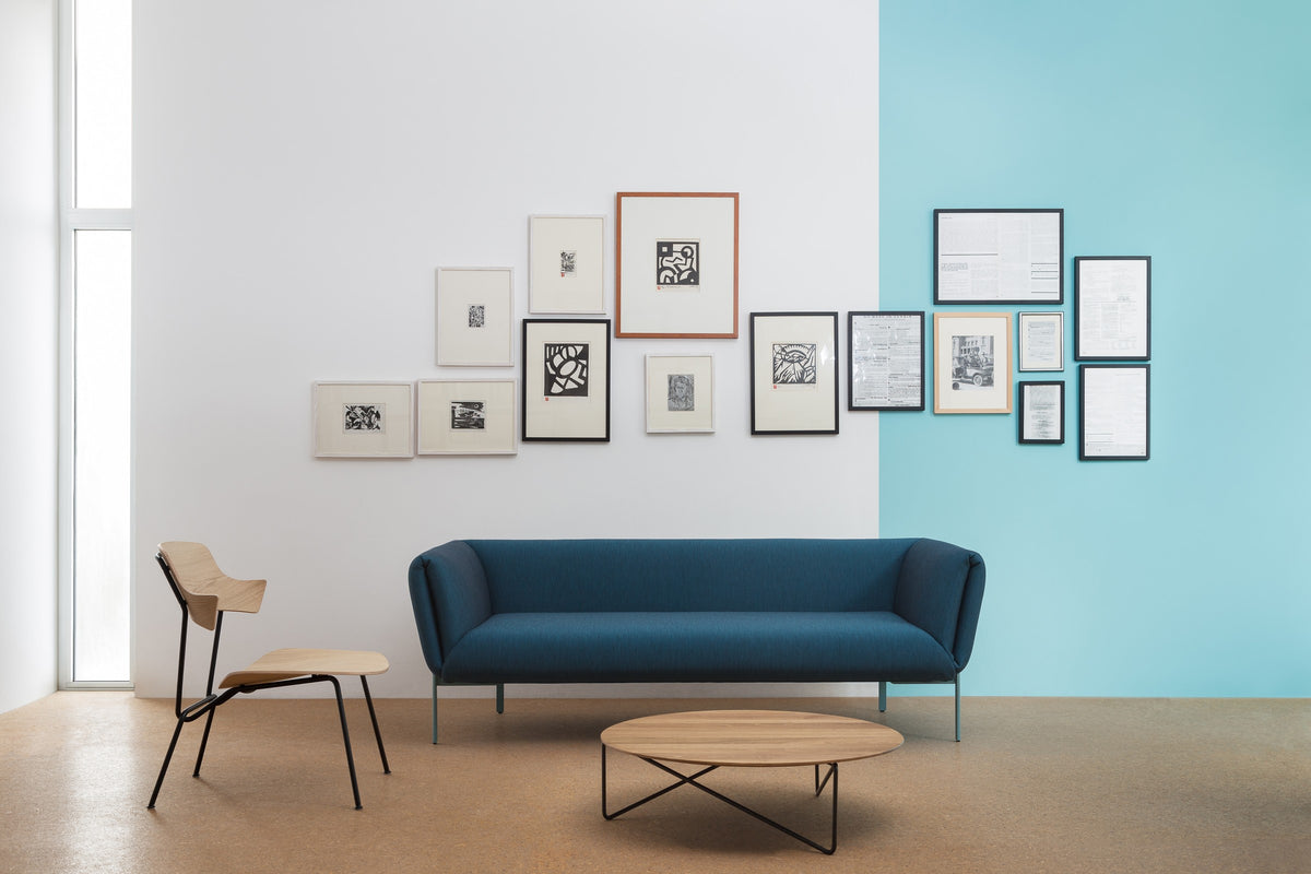 Impression Sofa von Prostoria in Blau an einer Bilderwand. © Prostoria