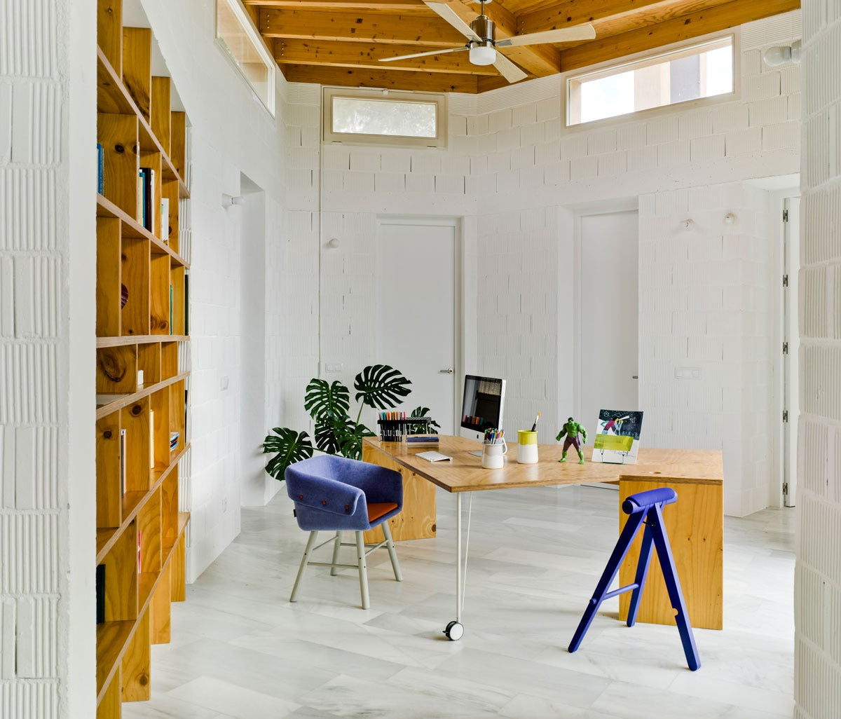 Sancal Collar Stuhl in Blau mit hellen Holzbeinen an einem Schreibtisch