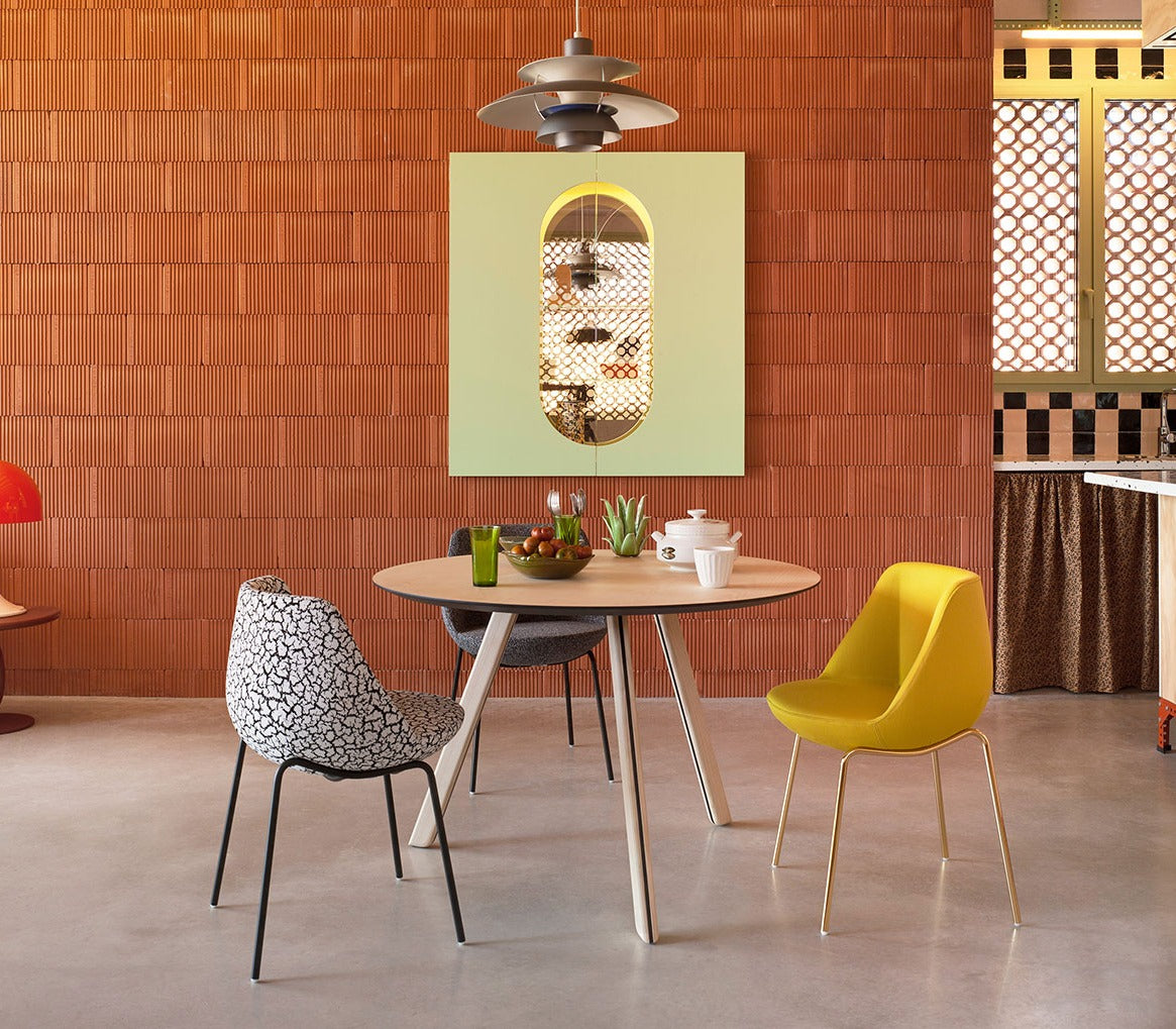 Sancal Magnum Stühle mit Metallbeinen an einem runden Tisch vor einer Ziegelwand