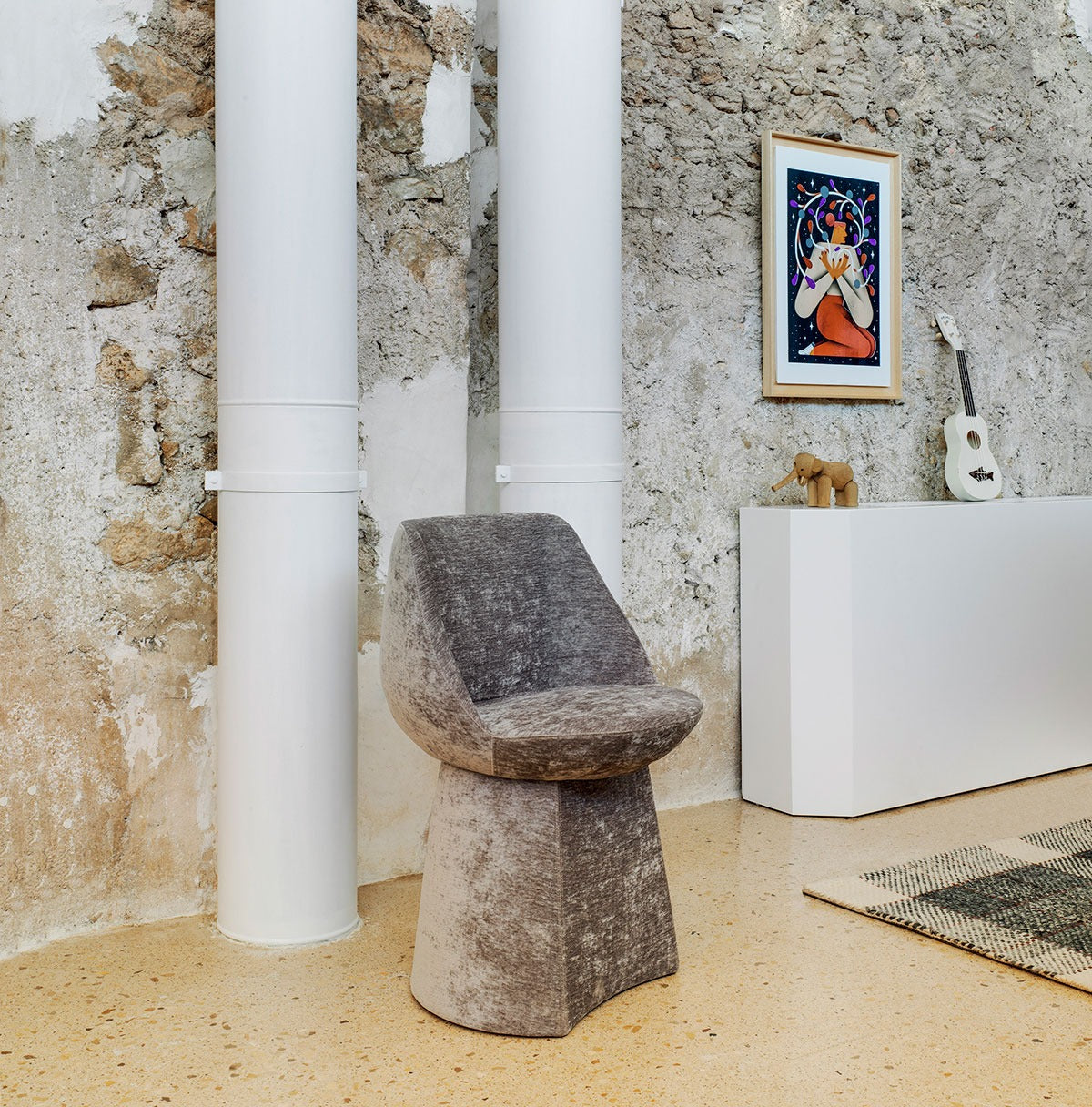 Sancal Magnum Stuhl in Grau mit gepolstertem Sockel vor einer Natursteinwand