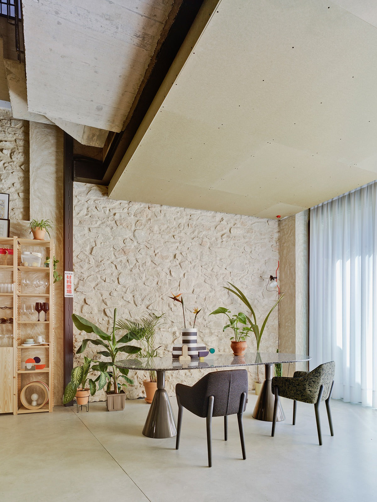 Zwei Sancal Nido Stühle mit Holzbeinen an einem ovalen Esstisch in einem hohen Raum