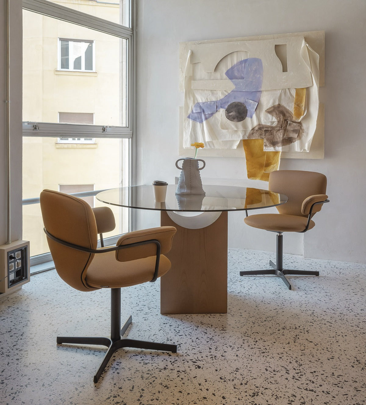 Zwei Sancal Planta Stühle mit Armlehnen in Cognac an einem runden Glastisch vor einem hohen Fenster