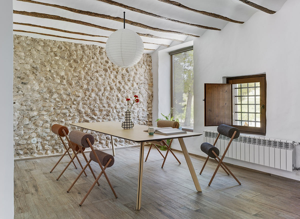 Sancal Roll Stühle an einem Holztisch in einem Esszimmer mit Natursteinwand