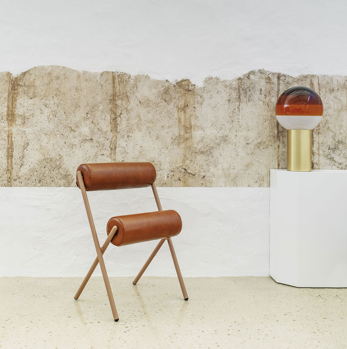 Sancal Roll Stuhl mit braunen Lederrollen und hellbraunem Gestell vor einer Wand mit Naturputz