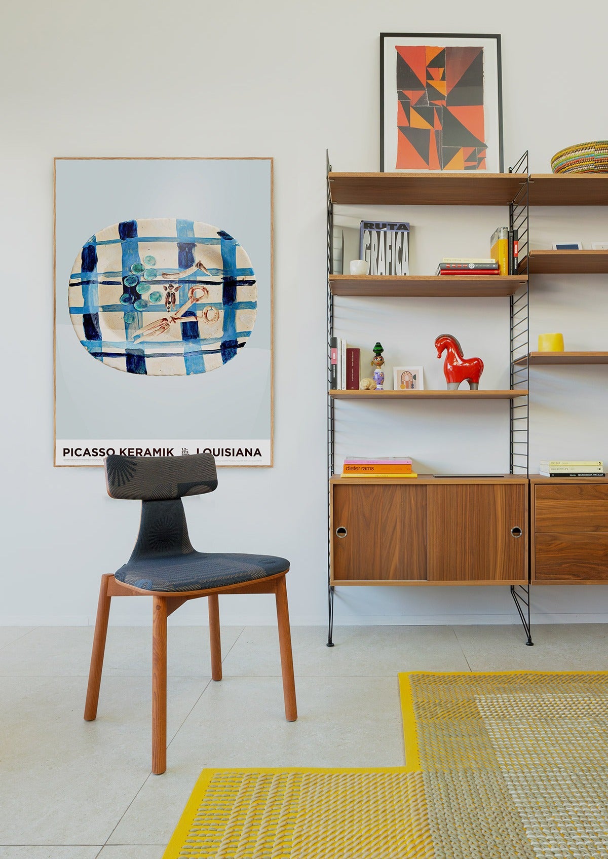 Sancal Silla40 Stuhl mit schmalem Rückenband, gemustertem Bezug in Anthrazit und rotbraunem Holz vor einem Wandregal