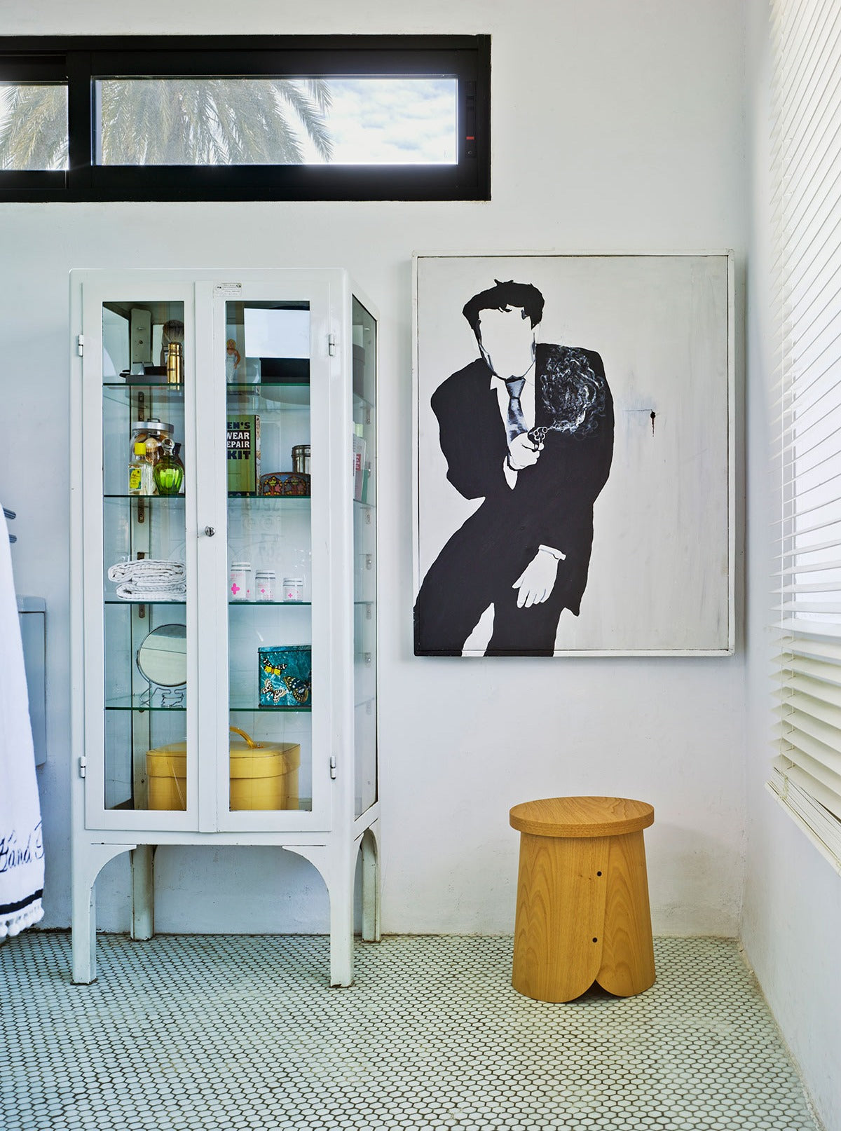 Sancal Tab Hocker aus Kastanie in einem hellen Raum neben einer Glasvitrine