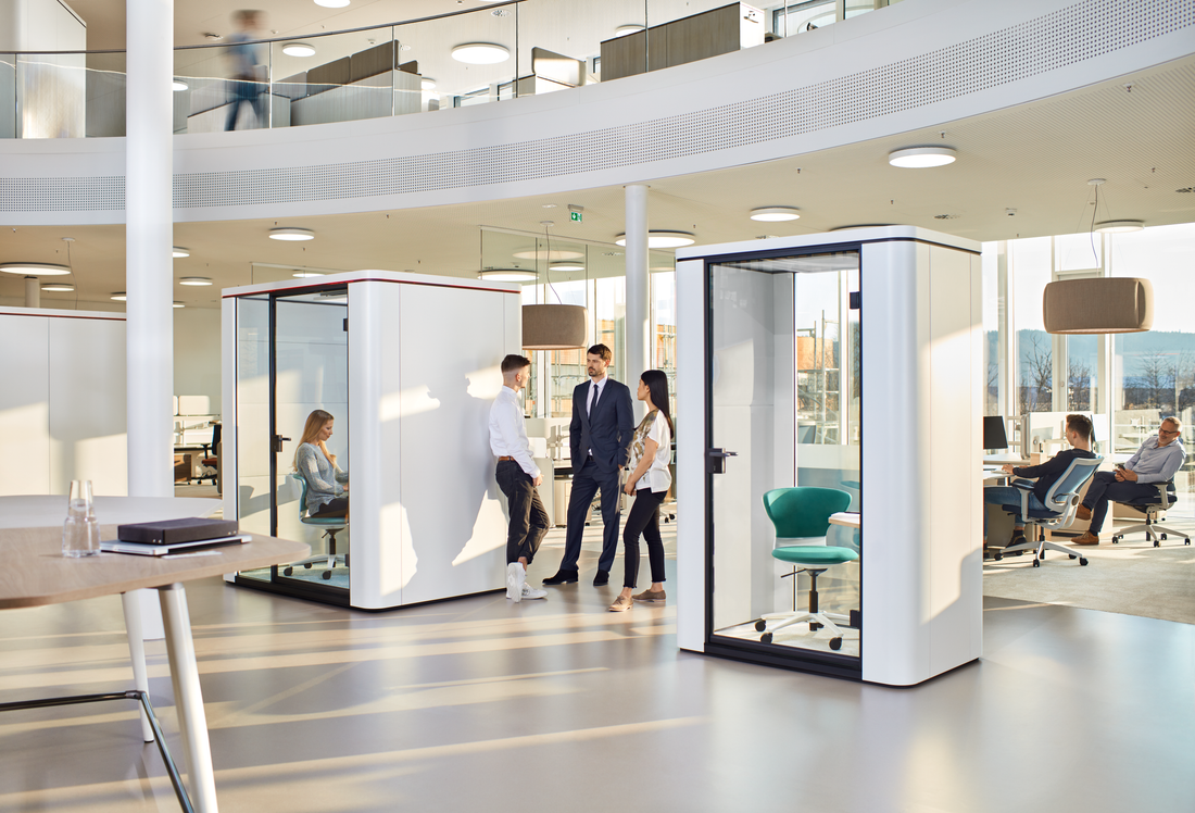 se:cube S – Telefonbox – Moderne Bürolandschaft mit zwei schallisolierten Glasbesprechungskabinen und mehreren Arbeitsplätzen im Hintergrund.