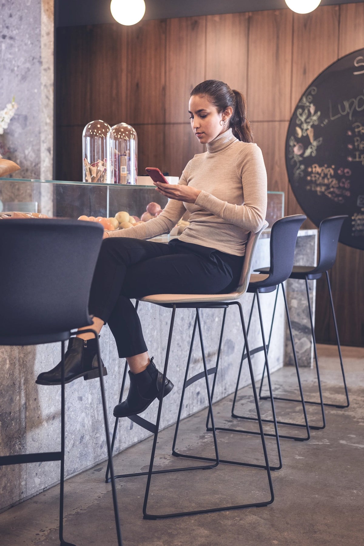 se:spot stool von Sedus mit Kufengestell, Person sitzt an einem Stehtisch.
