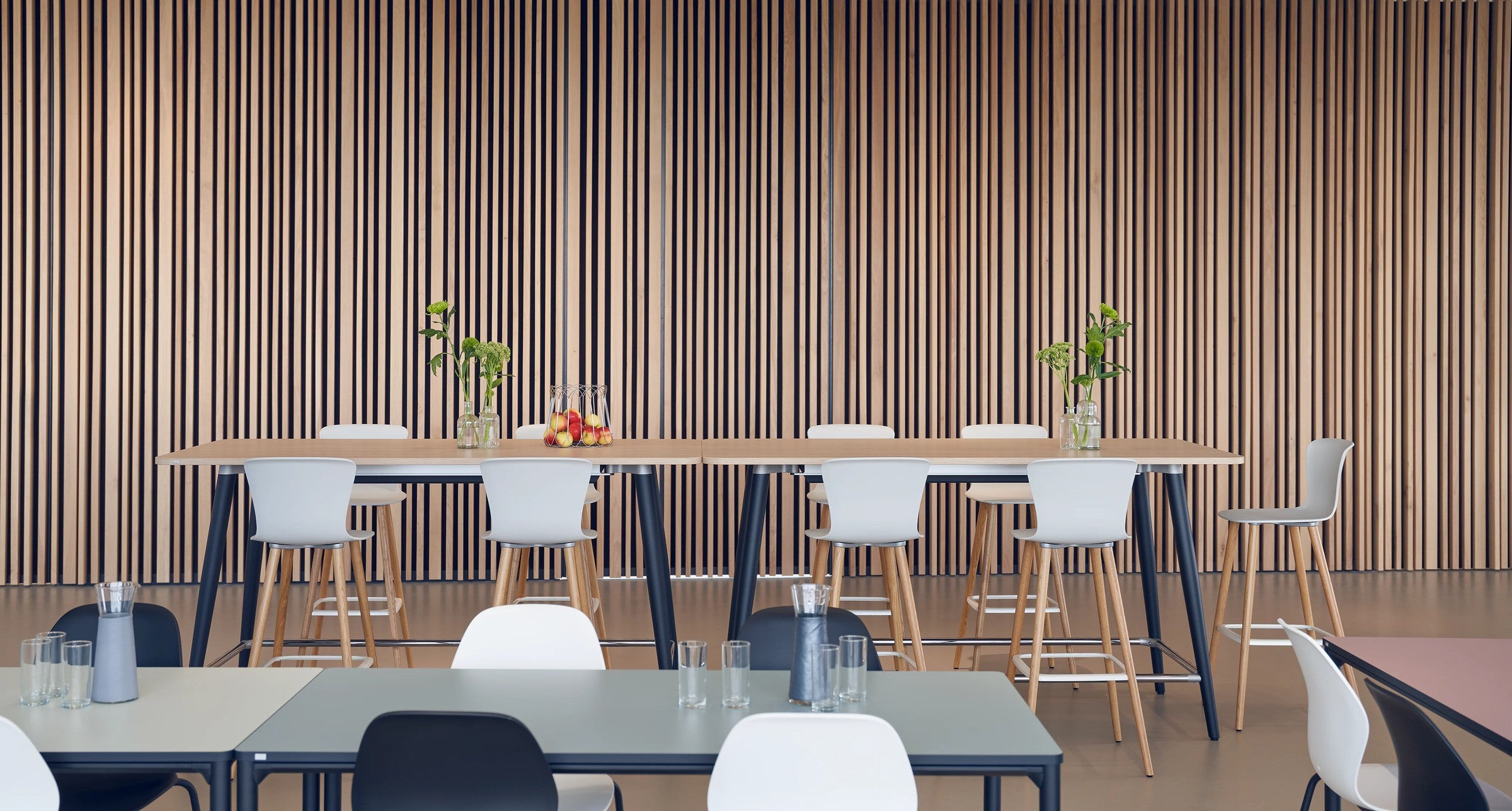 se:spot stool von Sedus mit Holzgestell an Hochtischen vor einer Lattenwand.