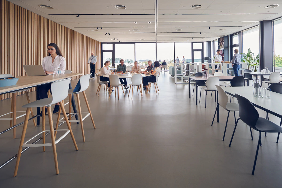 se:spot stool von Sedus mit Holzgestell an einem hohen Tisch, Cafeteria mit Fensterfront.