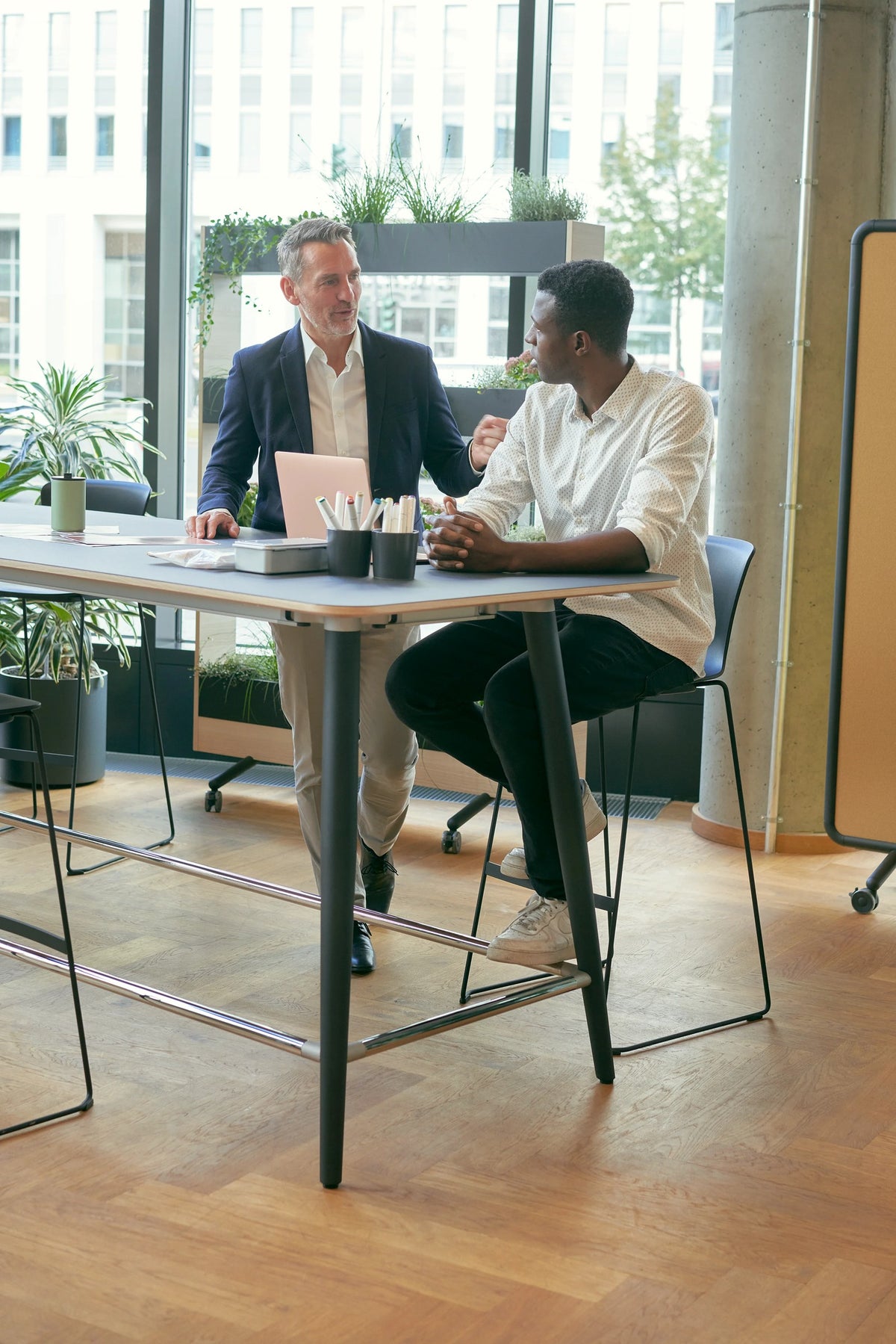 mastermind high desk – Hochtisch von Sedus – Zwei Personen an einem Hochtisch mit Barhockern.