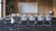 Klapptisch | Flip-Top – Klapptisch – Konferenzraum mit ovalem Tisch aus Holz und weissen Stühlen. An einer Wand befindet sich ein grosser, heller Bildschirm.