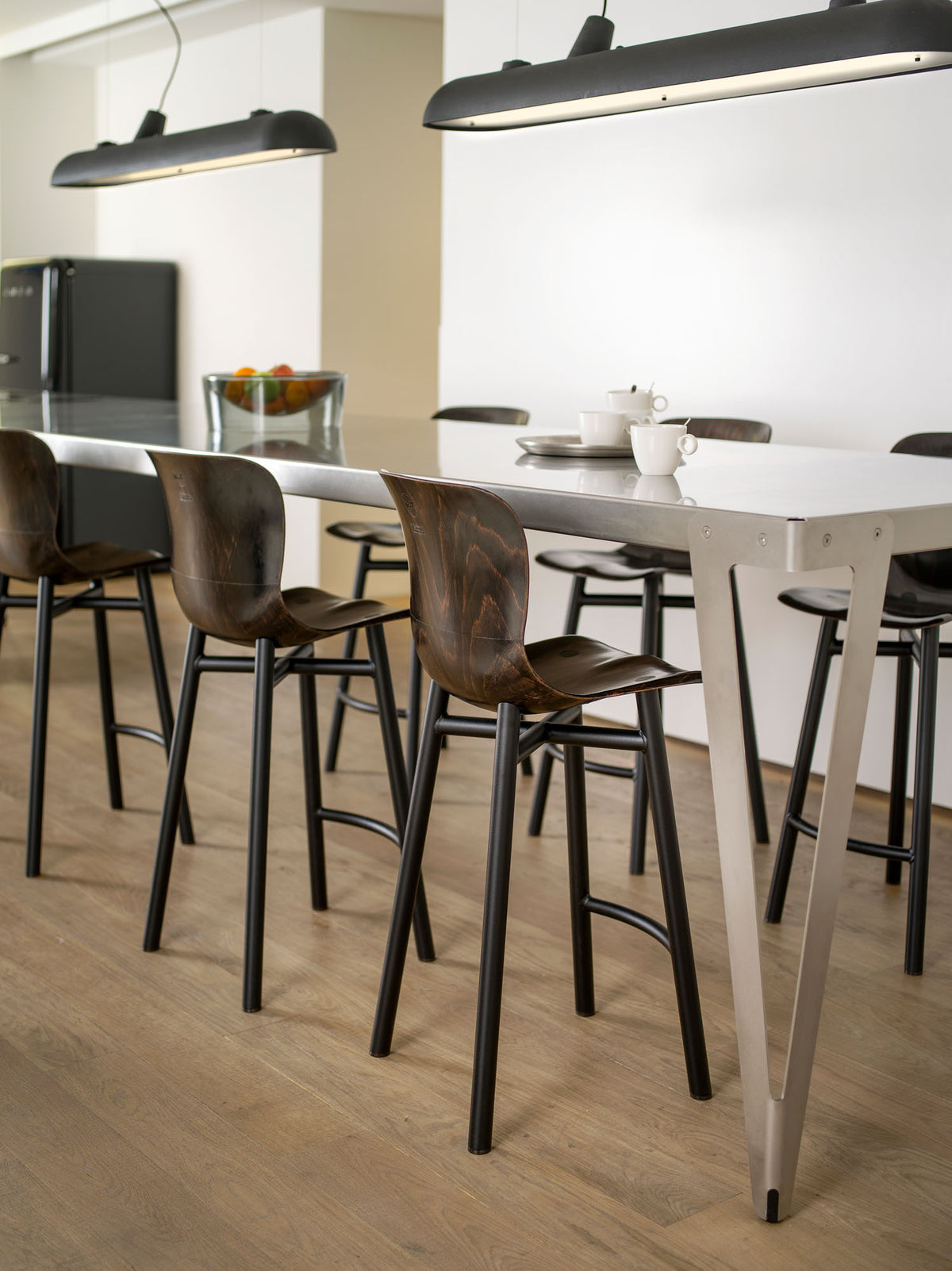 Wendela Barstool | Barhocker – Barhocker – Hochglanz-Tresen mit Metallgestell und Holzbarhockern in moderner Umgebung. Grosse Pendelleuchte über dem Tisch.